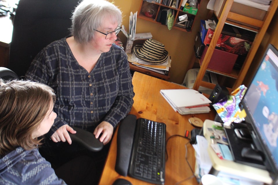 La mère et son fils sont devant l'ordinateur.