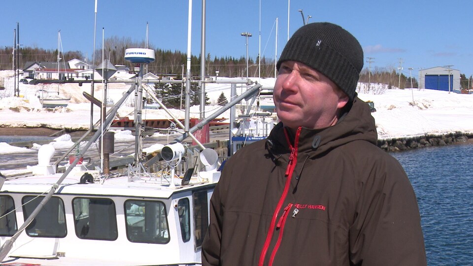 Un pêcheur debout près de son bateau