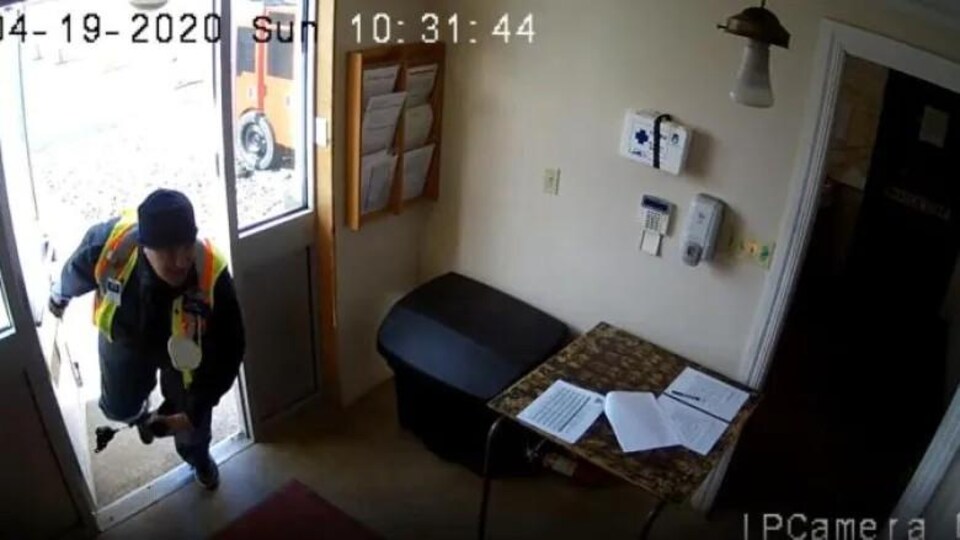 A surveillance camera shows a man bent over, entering the fire station.