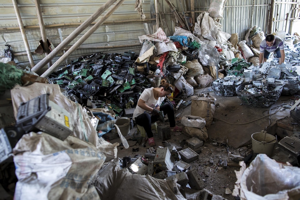 Une travailleuse démantèle des lecteurs CD dans un entrepôt de Guiyu en Chine. 