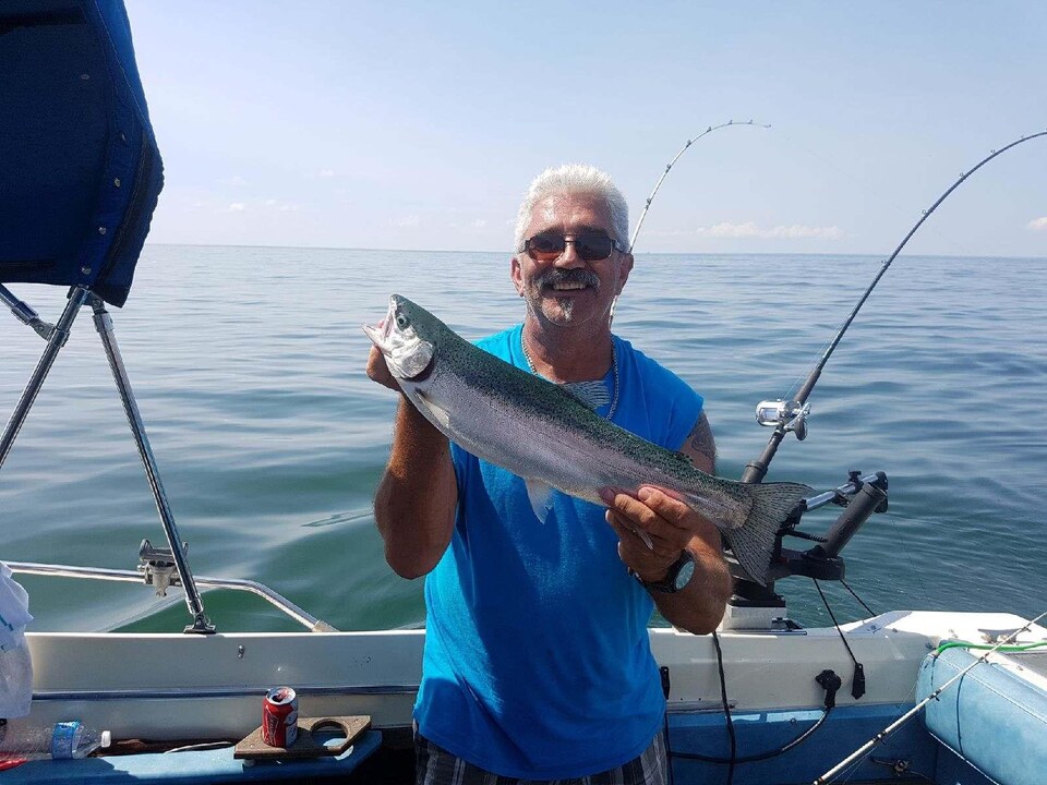 On voit M. Marotte dans son bateau de pêche, souriant à la caméra avec un poisson dans les mains. Derrière lui, la surface du lac Érié par une journée ensoleillée.
