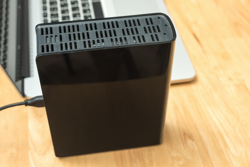 Un disque dur externe sur un bureau près d'un ordinateur portable.