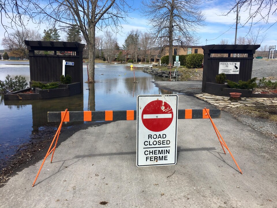 Un panneau ferme l'accès à une route inondée.