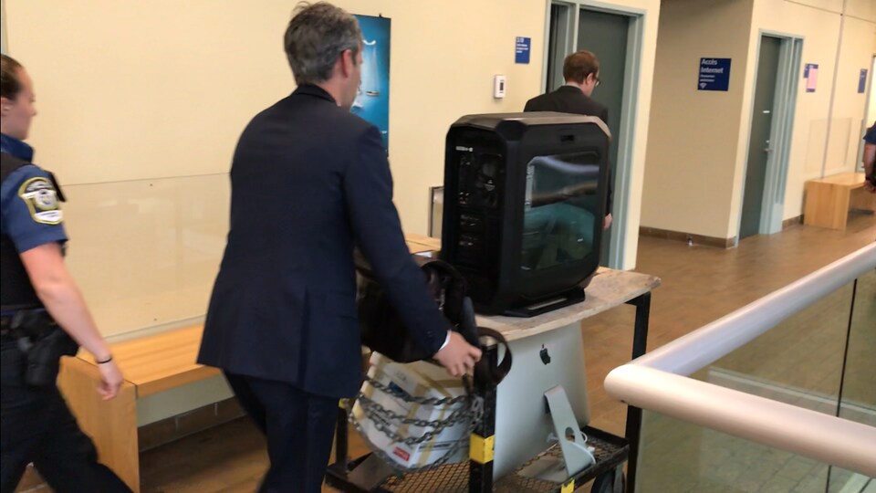 Un homme transporte du matériel informatique à l'aide d'un chariot dans les couloirs du palais de justice de Québec.