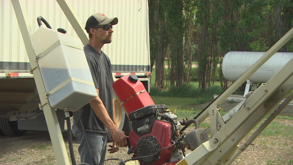 Don McLean manipule une machine agricole qui transfère le grain du silo à son camion.