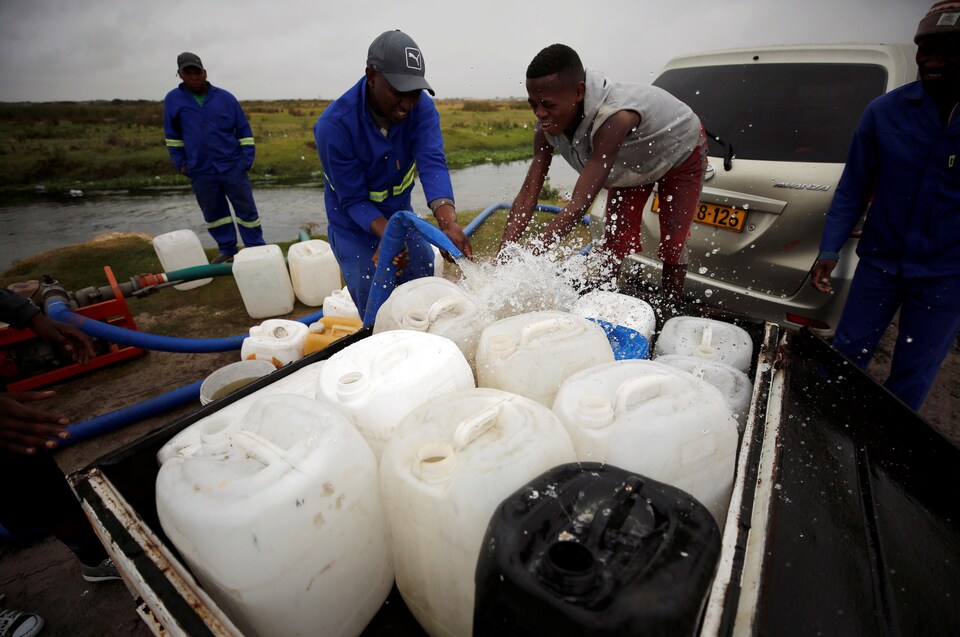 Des Africains pompent de l'eau dans des réservoirs. 