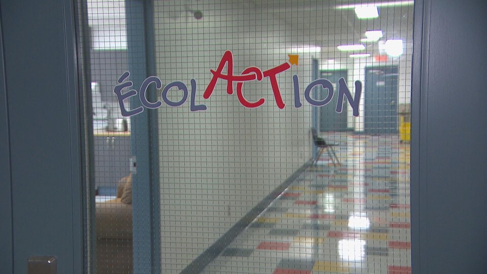 Le nom ÉcolACTion imprimé sur la fenêtre d'une porte intérieure de l'école.