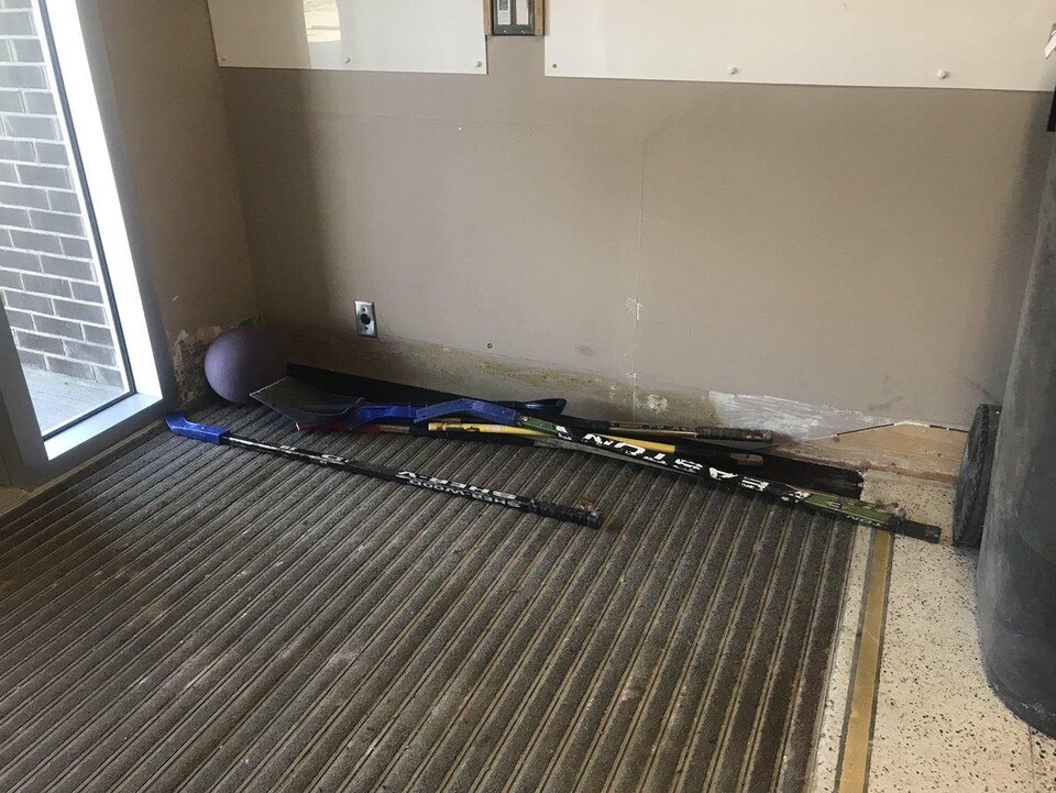 Un ballon et des bâtons de hockey sont déposés au sol dans une entrée de l’École Mgr-Feuiltault. Le bas des murs porte des traces de l’inondation.