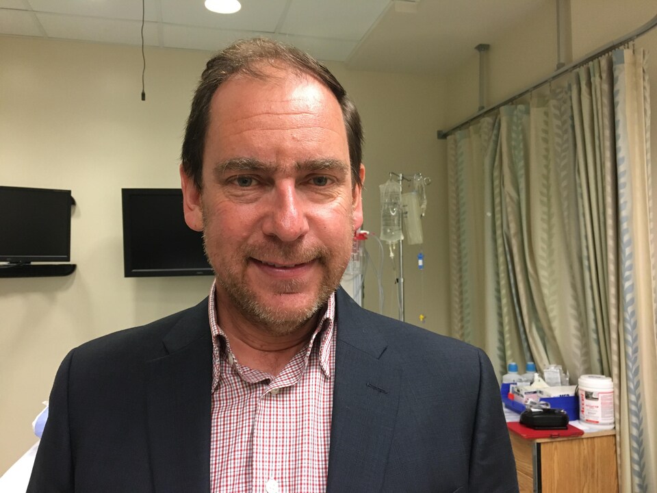 Le docteur sourit à l'appareil photo dans une salle d'examen médical. 