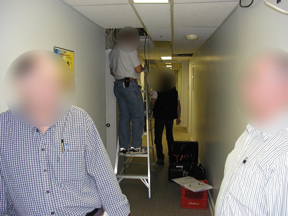 Des hommes en train d'installer des fils dans le plafond. 