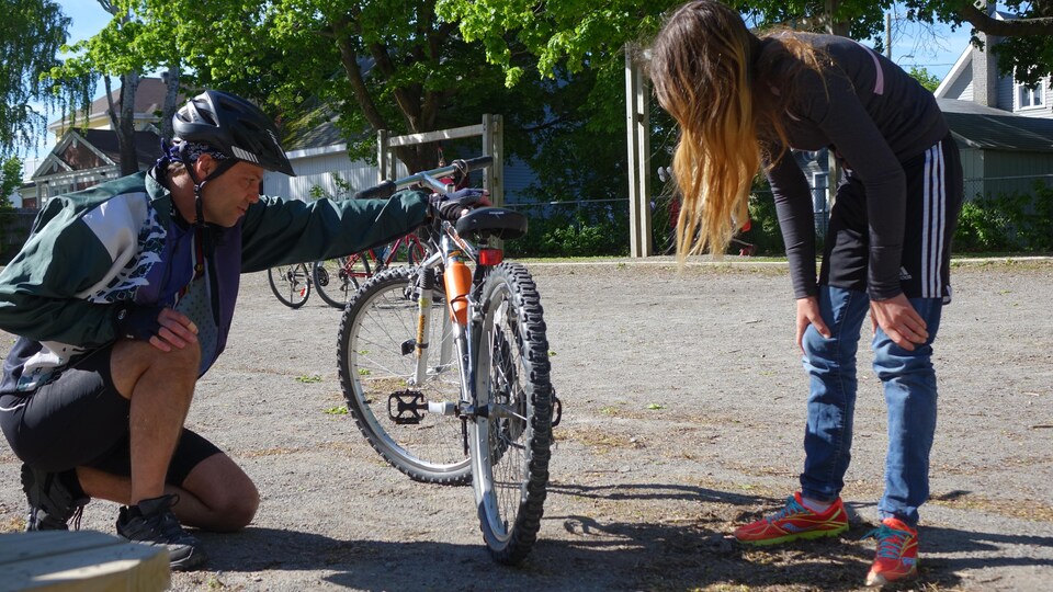Un homme et une élève vérifient l'état d'un vélo.