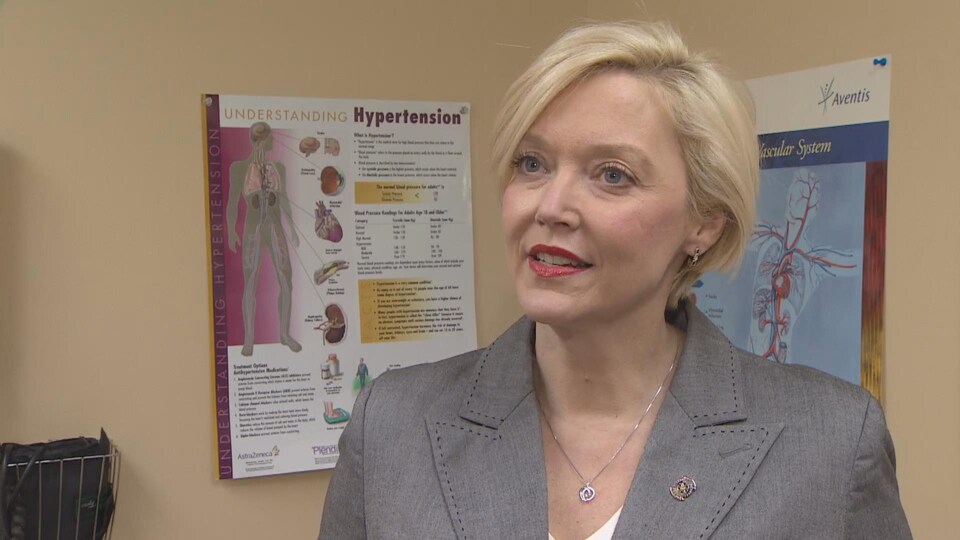 Elizabeth Smith-McCrossin devant une affiche sur l'hypertension.