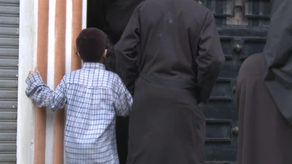 Un petit garçon et des membres de Lev Tahor, devant une porte au Guatemala.