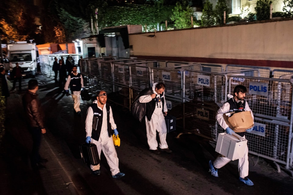 Des policiers turcs munis de combinaisons spéciales transportent des boîtes à la brunante.
