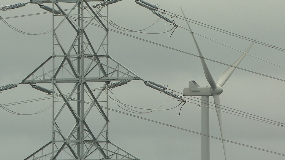 Une éolienne derrière des fils électriques