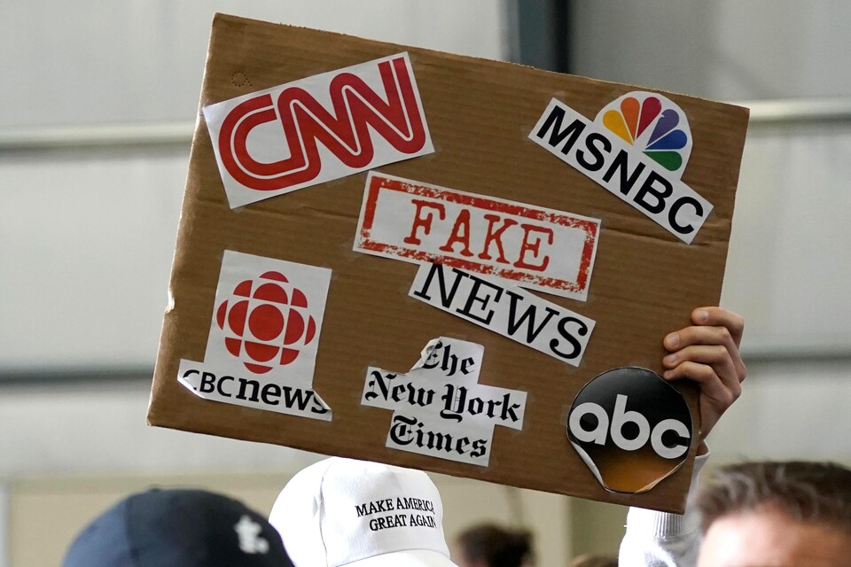 Un partisan du président Donald Trump brandit une pancarte associant les fausses nouvelles à des médias tels que CNN, CBC News et le New York Times.