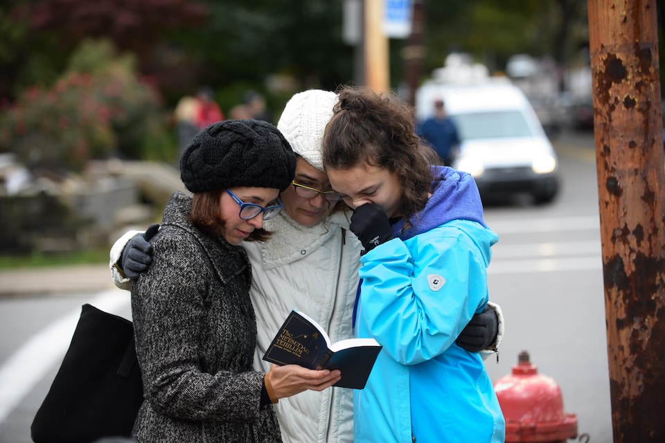 Trois femmes se recueillent en lisant un livre de prières juives près de la synagogue où a eu lieu la fusillade meurtrière, à Pittsburgh. 
