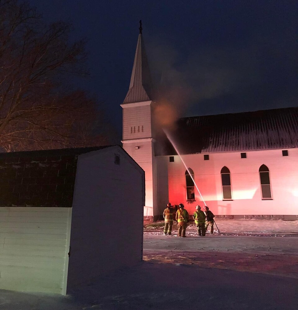 Des pompiers arrosent l'église.