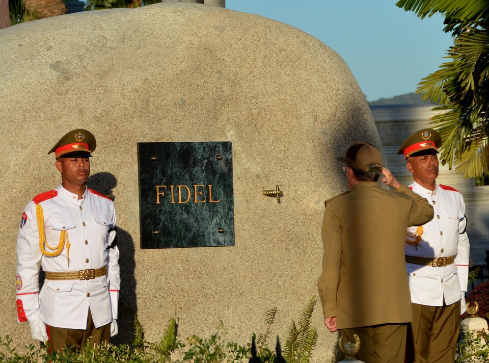 Le président cubain Raul Castro fait un salut militaire devant la tombe de son frère, Fidel Castro, gardée par deux soldats.