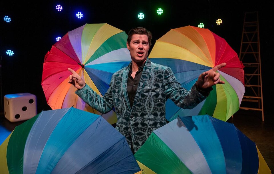 Un homme se tient devant des parapluies multicolores.