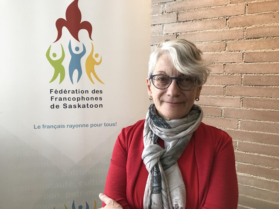 Francine Proulx-Kenzle devant une affiche de la FFS à Saskatoon