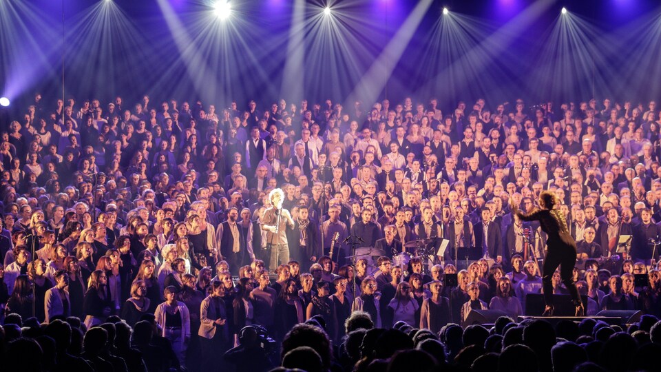 Gens qui chantent avec Fred Pellerin au centre et une cheffe de choeur