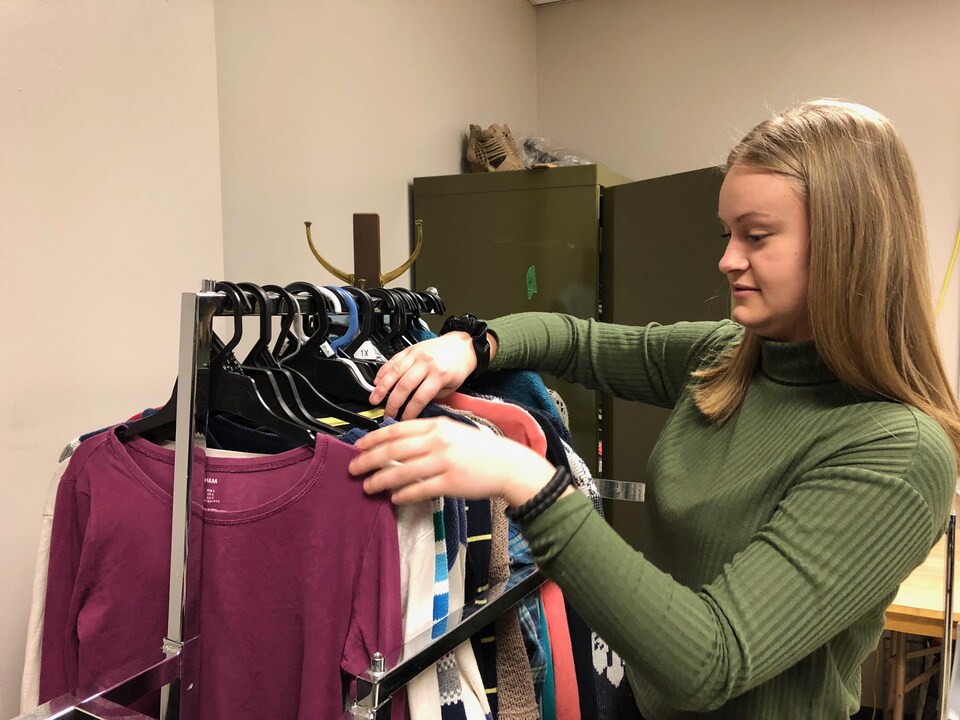 Une adolescente regarde un présentoir à vêtements. 