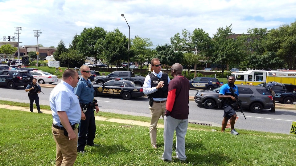 Des policiers interrogent un homme près du lieu de la fusillade à Annapolis, au Maryland. 