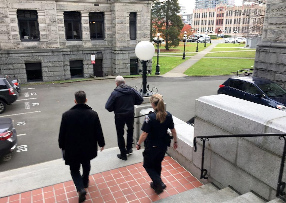 Gary Lenz descend un escalier, suivi par une agente de la GRC et un homme habillé en civil.