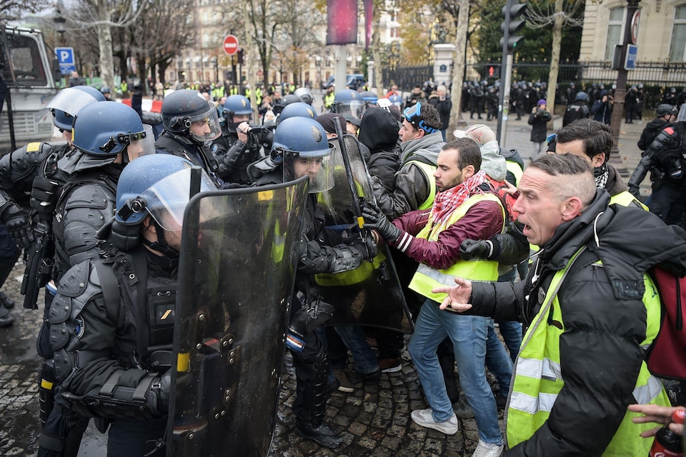 Des policiers antiémeutes font face à des manifestants en colère dans une rue.