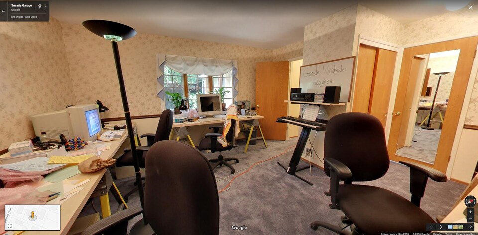 Une photo montrant une pièce dans une maison aménagée en bureau. Des pupitres et des ordinateurs s'entassent le long des murs.