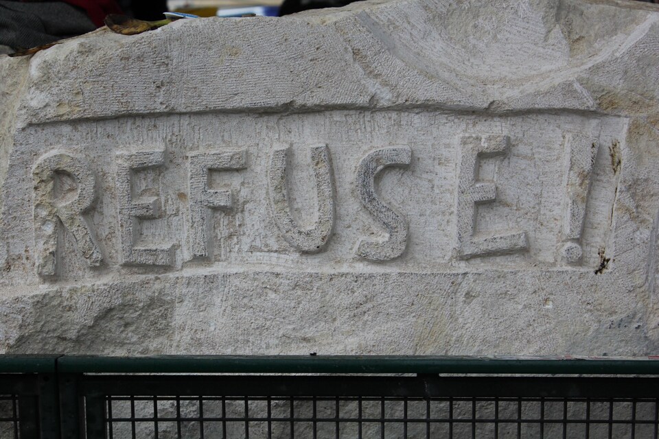 Inscription dans une pierre, près de tentes de migrants à Paris