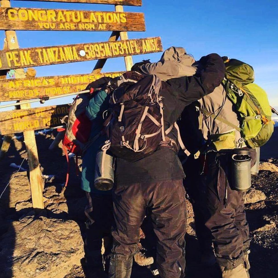 Les amis s'étreignent au sommet du Kilimandjaro.