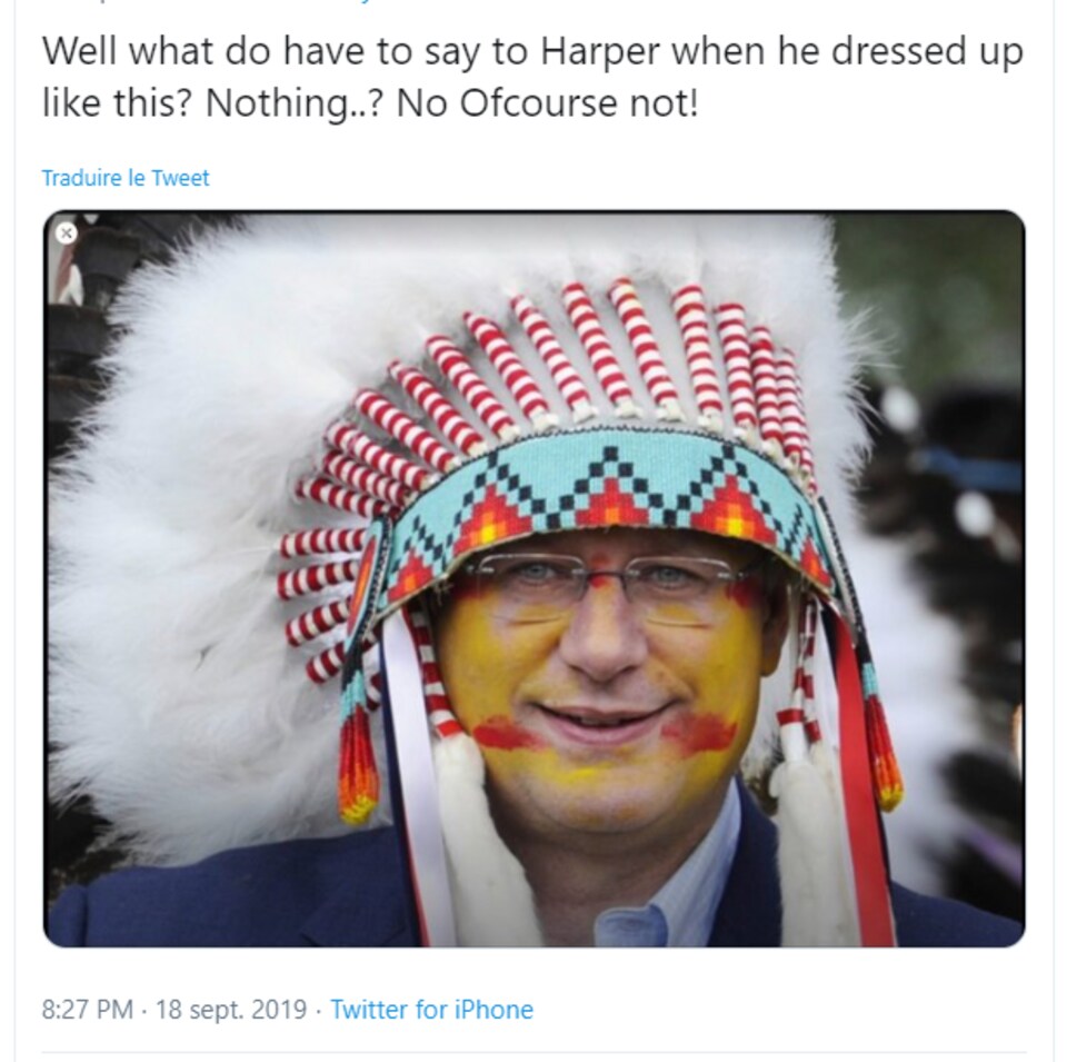 M. Harper a le visage peint et porte une coiffe autochtone.