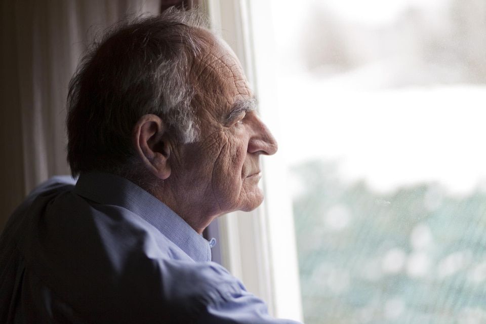 Un homme âgé regarde par la fenêtre.