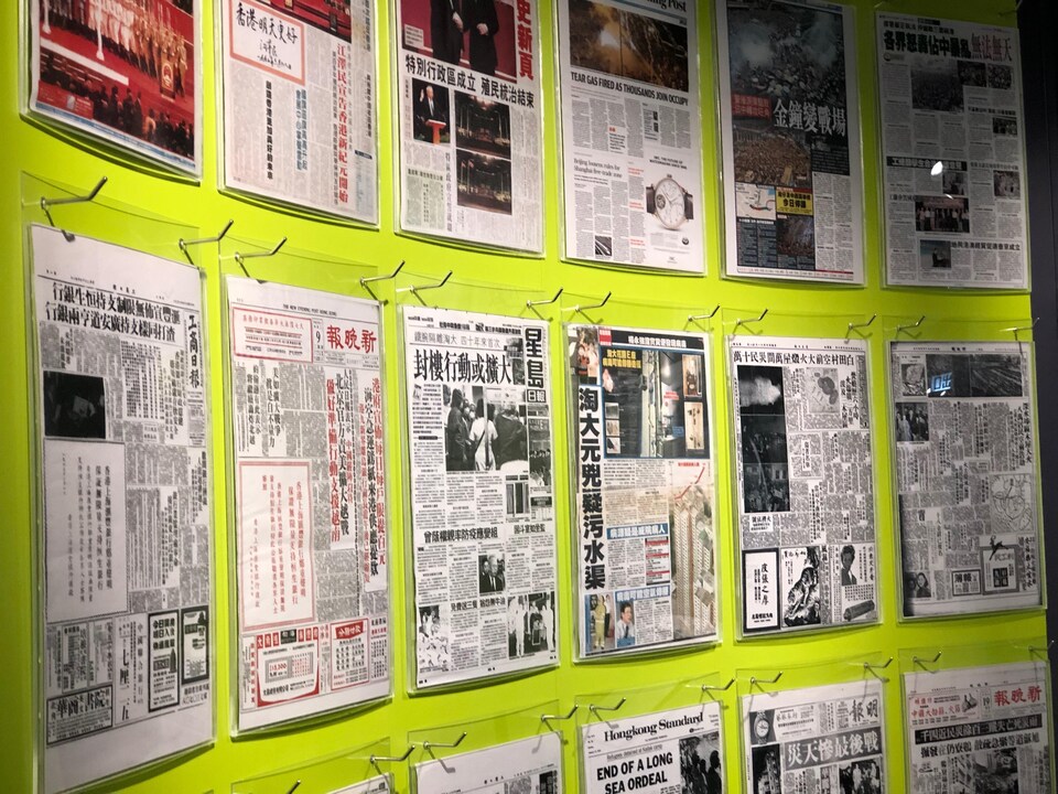 Des pages de journaux sont exposées sur un mur.