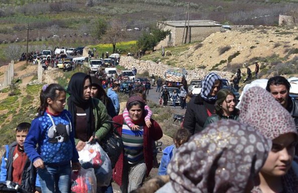 Des familles marchent sur une route montagneuse, des bagages en main.
