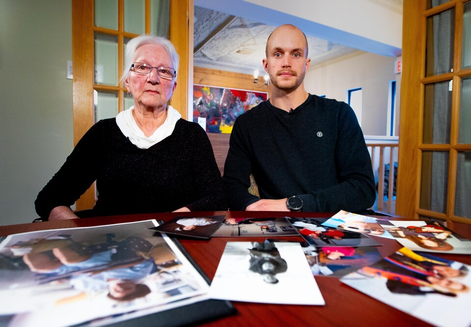 Les deux sont assis devant une table remplie de photos de famille. 