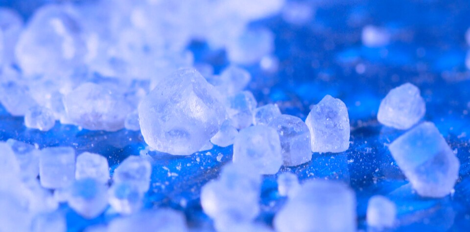 On voit en gros plan les cristaux transparents, sur fond bleu.