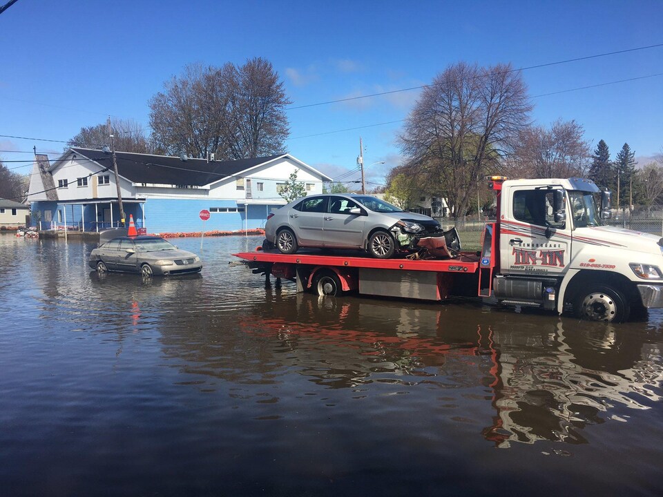 Des marques du niveau de l'eau apparaissent sur une voiture qui émerge des inondations.