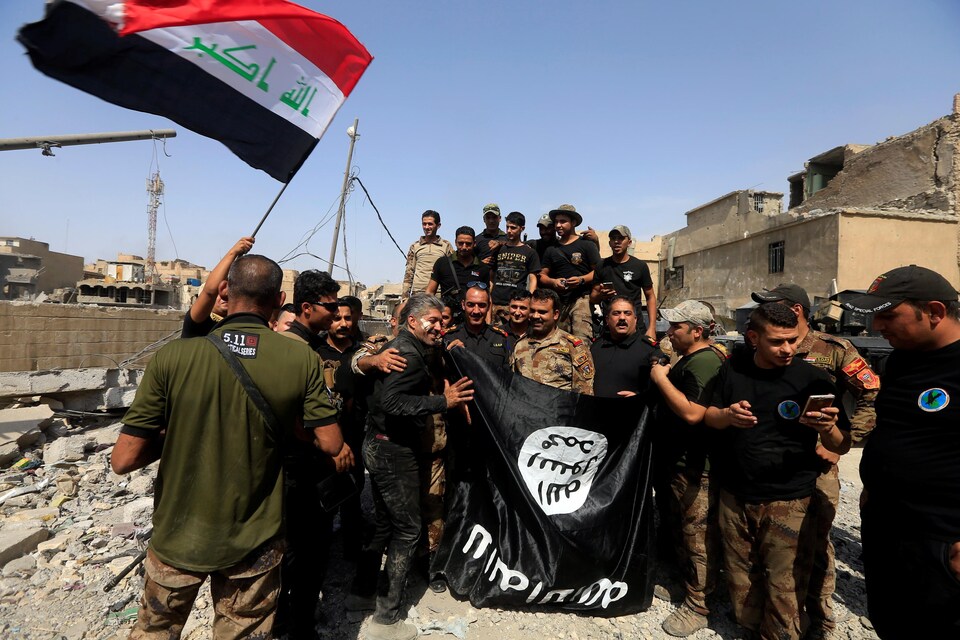 Des membres des forces irakiennes de contre-terrorisme brandissent un drapeau de l'État islamique.
