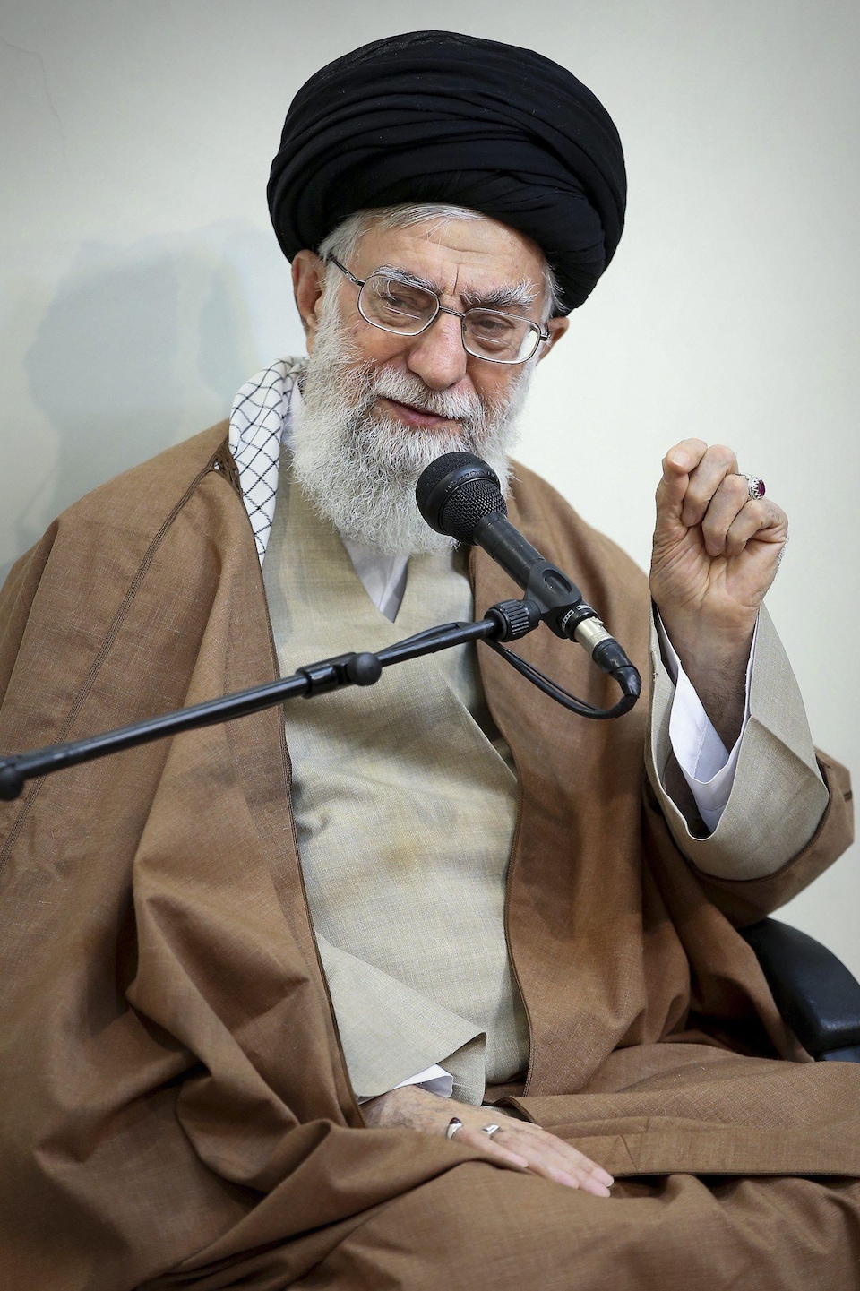 Plan rapproché de l'ayatollah Khamenei qui parle dans un micro en levant la main.