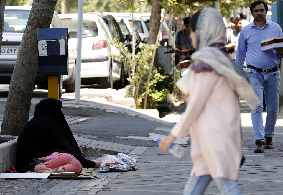 Une femme portant le tchador est assise sur un trottoir de la capitale pour demander la charité. 