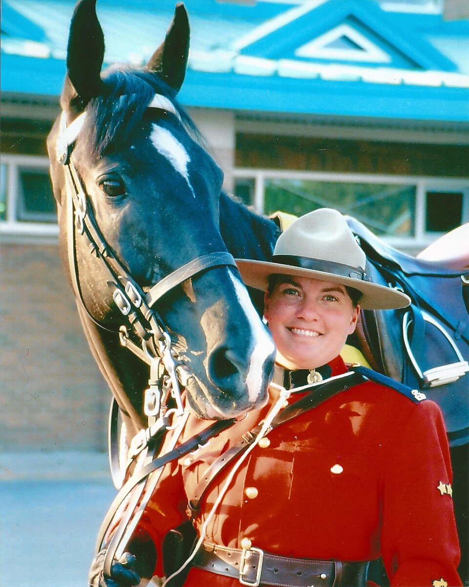 Une femme dans l'uniforme traditionnel de la GRC, avec un cheval. 