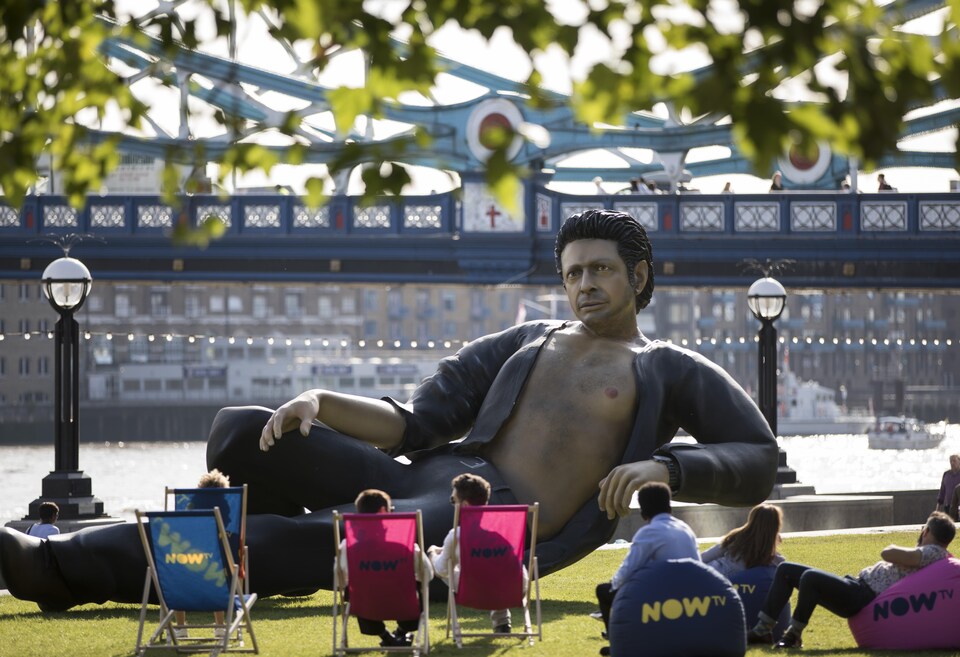 Des passants sont assis à côté de la statue géante de Jeff Goldlbum, installée à Londres.