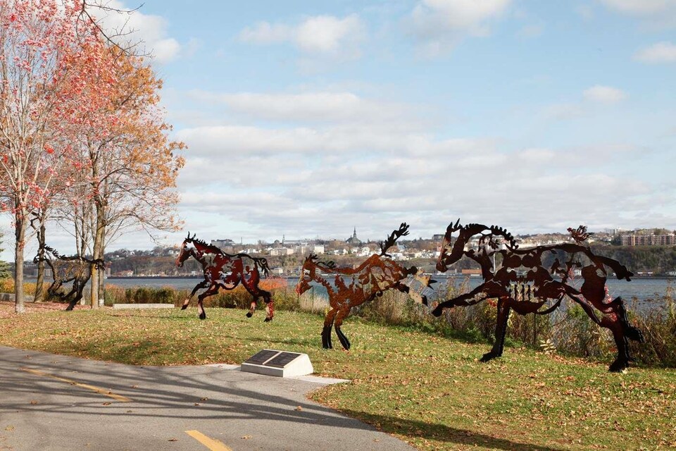Une sculpture représentant des chevaux en mouvement dans un parc.