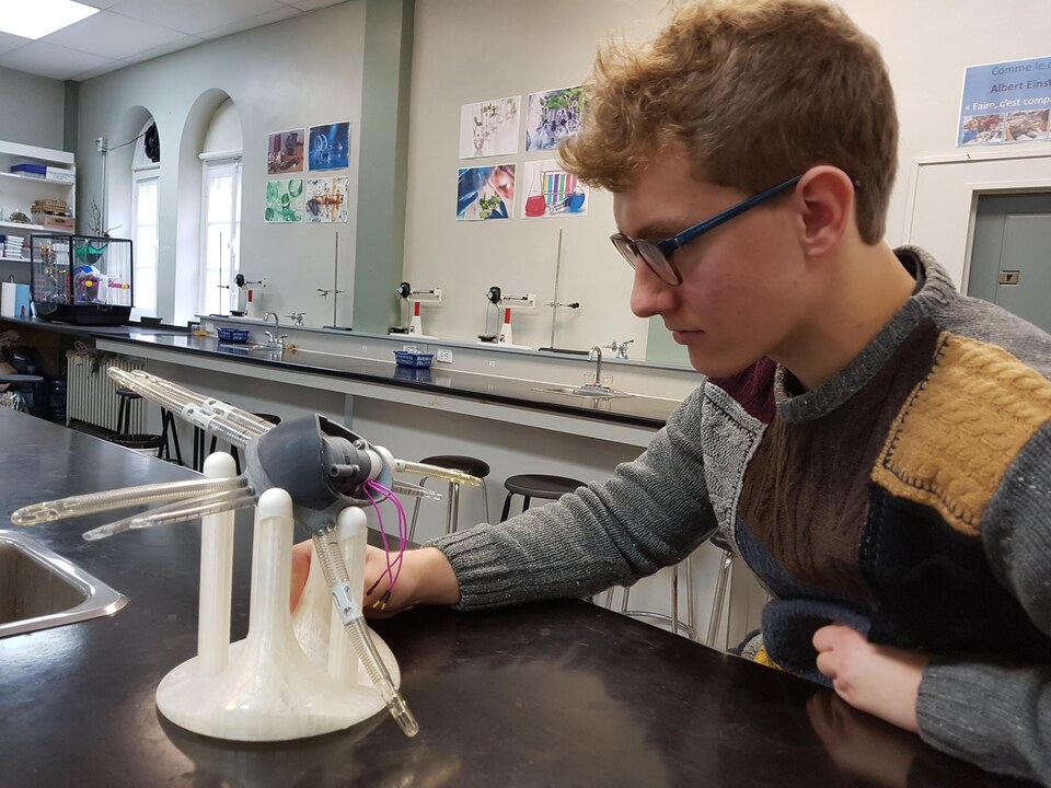 Le jeune Jonathan Lévesque regarde un prototype de cœur artificiel qu'il a conçu.