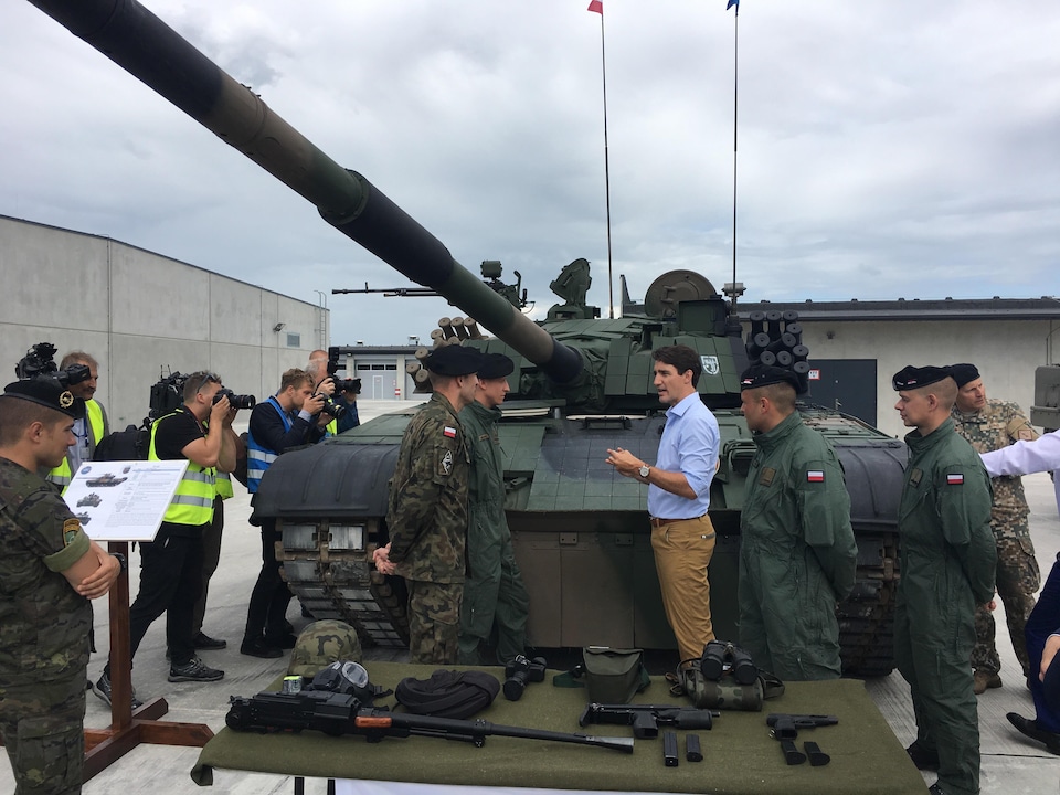 Justin Trudeau parle à des militaires devant un char d'assaut.