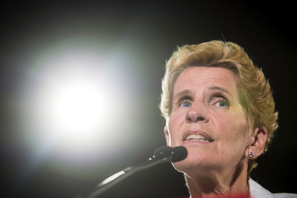 Photo de Kathleen Wynne au micro, la lumière d'un projecteur en arrière-plan