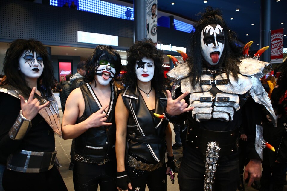 Quatre fans du groupe Kiss portant des déguisements et du maquillage lors du spectacle de la formation à Québec en avril 2019.